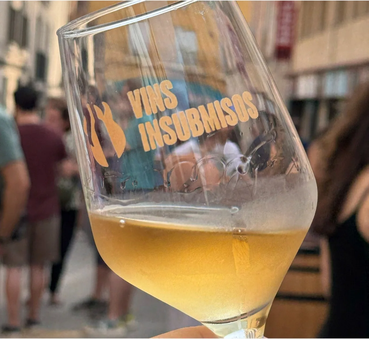Copa de vi amb el logotip de Vins Insubmisos serigrafiat, en un carrer de Vilafranca